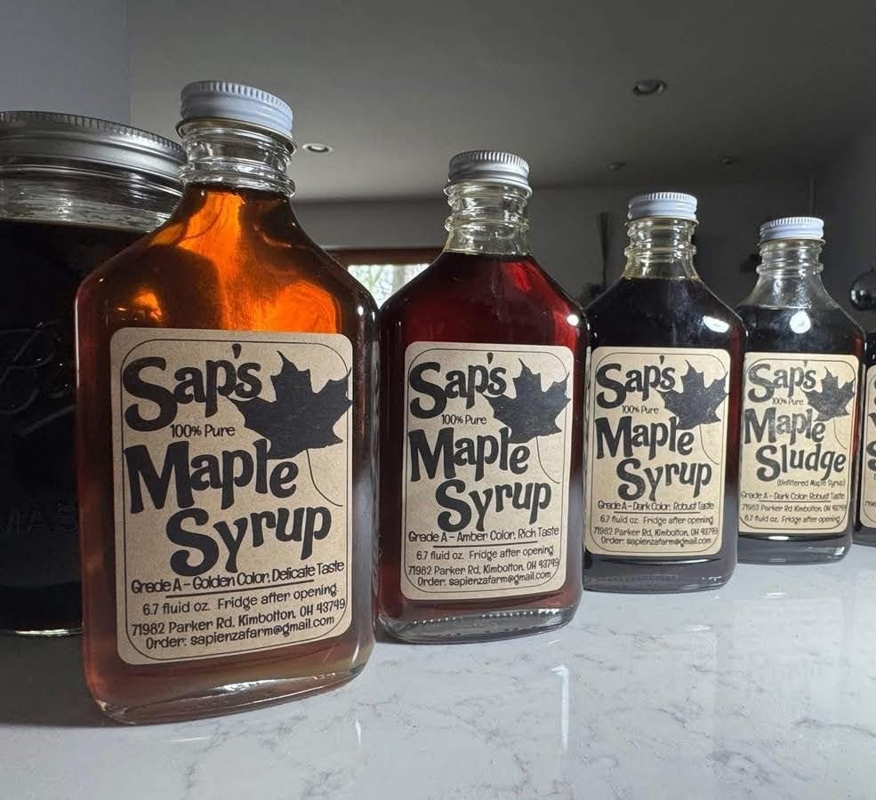 Four bottles of Sap's syrup in a row: golden, amber and dark maple syrup, and Maple Sludge