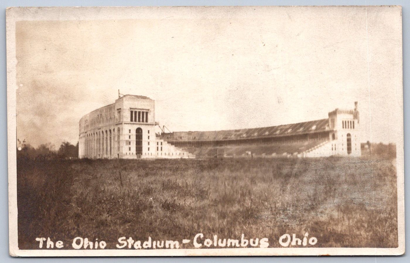 Sepia real photo postcard of the Ohio Stadium in Columbus, Ohio, a large concrete stadium rising over an empty field
